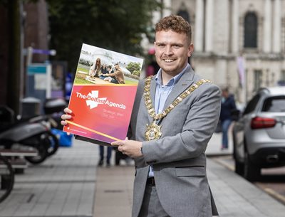 Belfast Lord Mayor Councillor Ryan Murphy holding copy of the Belfast Agenda on city centre street
