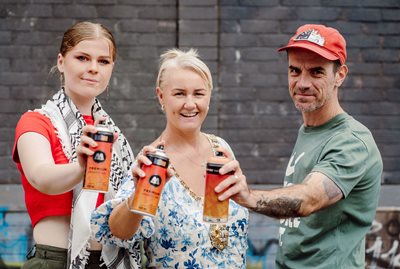 Lord Mayor of Belfast, Councillor Tracy Kelly, and street artists Sarah (left) and Ray Bonner (right) hold spray cans at the city's first legal street art wall in Little Patrick Street.