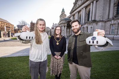 Three people outside Belfast City Hall, two are holding VR headsets